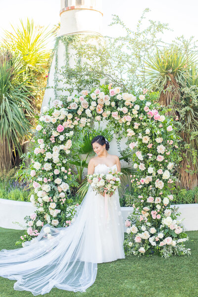 Bride under floral arch at Tivoli in Fallbrook, California.