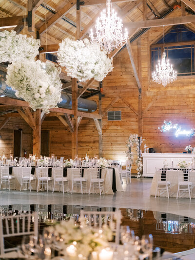 Indoor shot of reception venue with set tables and florals hanging from the ceiling