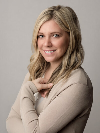 female headshot wearing white shirt with gray background