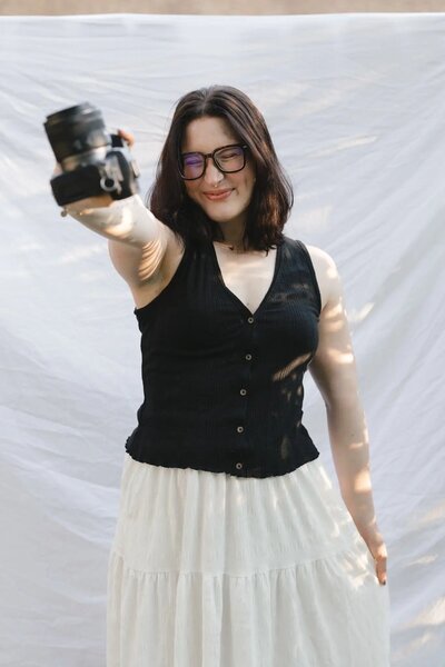 Playful headshot of Hope Hoggard holding her camera forward.