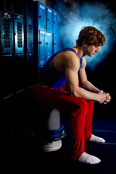 Focused young male gymnast photographed by Brooke Tucker Photography during a Grit & Glory athlete session in the locker room- capturing strength, discipline, and quiet intensity