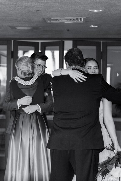 Newlyweds hugging two wedding guests and smiling 