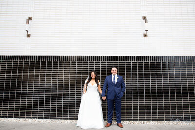 Austin-based wedding photographer capturing a bride and groom in front of a brick wall.