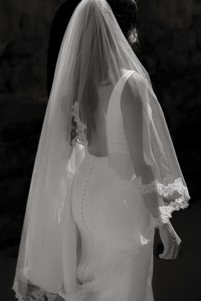 Black and white photo of bride from behind with a long veil on