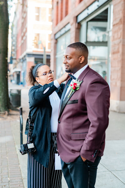 A photographer helping a person adjust their suit jacket