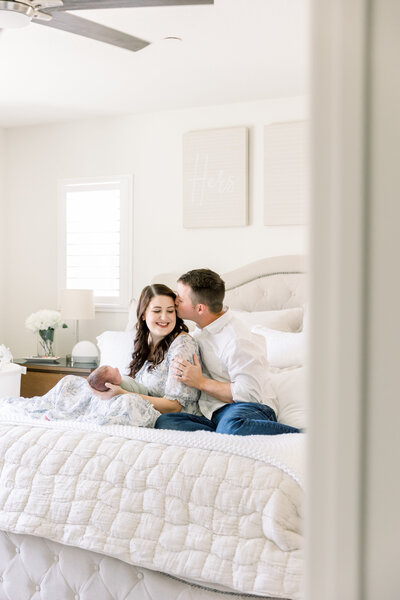 couple sitting on bed holding their newborn baby taken by Sacramento Family Photographer Kelsey Krall