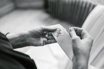 Black and white image of hands pinning a cross