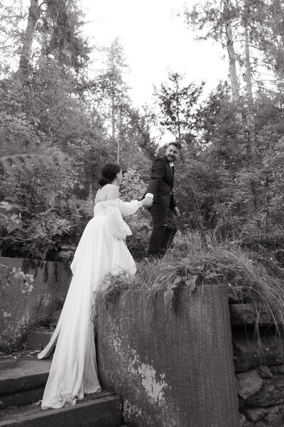 Groom leading bride up staricase at rockefeller mansion in vermont