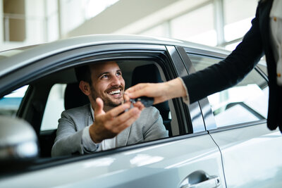 smiling man accepting keys to a new car