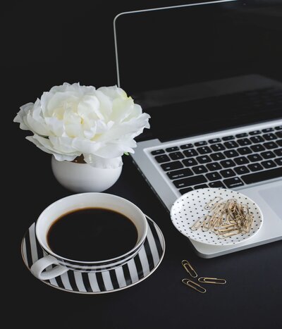 black background white flowers black and white tea saucer with tea black and white polka dot dish with gold paper clips on a laptop