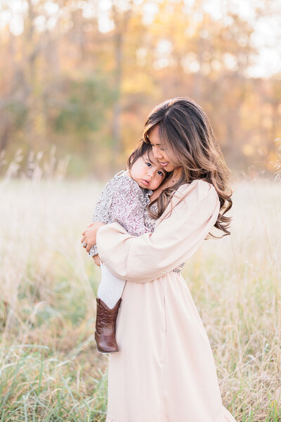 A tender moment between a mother and her baby, captured in soft natural light as they cuddle closely.