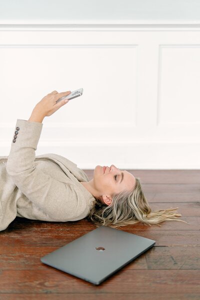 A woman laying on the ground looking up at her iPhone