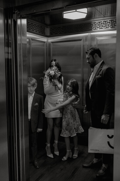 Black and white image of bride and groom and their two kids in an elevator