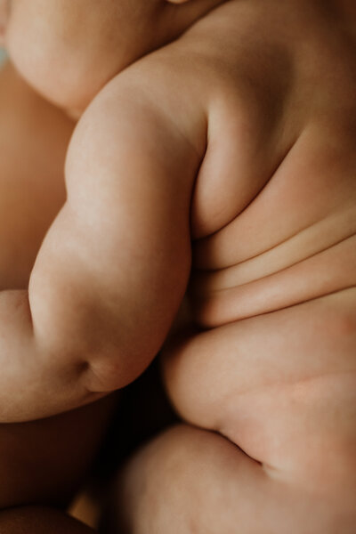 Close-up of a newborn’s soft skin and baby rolls, capturing the delicate textures and natural beauty of early life.