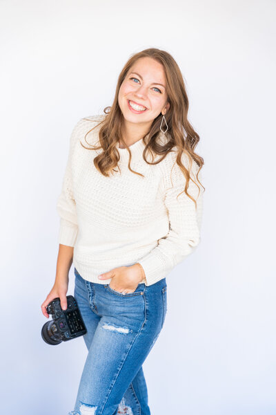 miranda in blue jeans and white sweater holding camera