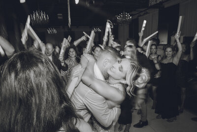 Emotional hug on the dance floor surrounded by guests at wedding reception