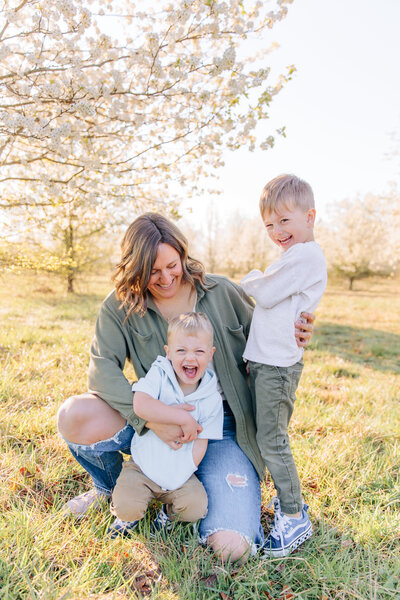 Mom of two toddler boys tickles them during Spring bloom photo session with Asheville Family photographer Rachel Marie Photography