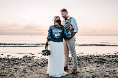 De bruid draagt witte henna, trouwjurk van de Bruidszaak in Purmerend en  leerjasje van Aim Your Weddings