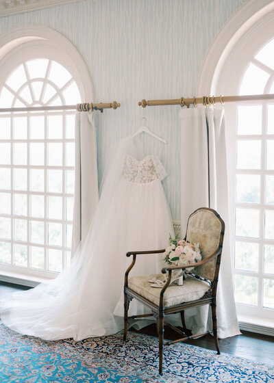 Brides wedding dress hanging on hanger with floral arrangement sitting next to her in Virginia wedding photographer detail shots 
