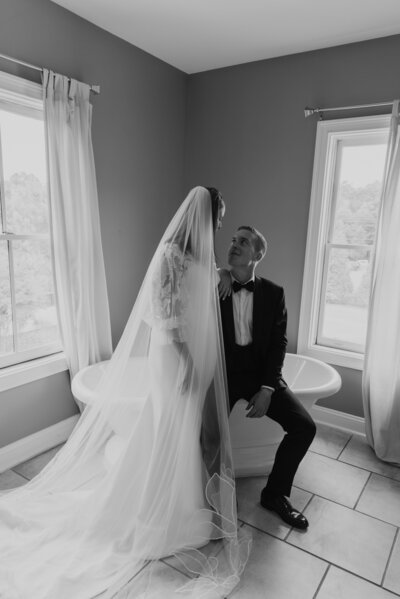 Bride and groom sit on a clawfoot bathtub