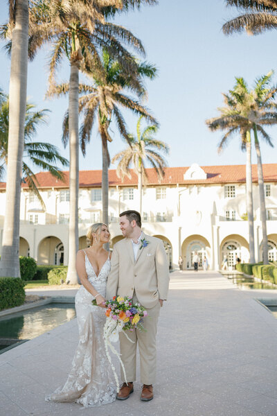 couple walking down the middle of the sidewalk with the casa marina hotel in the background