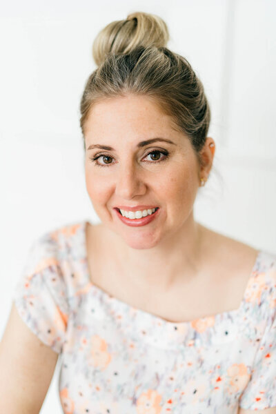 Headshot of a young woman in floral shirt and hair in a bun at The Maine Photo Studio in Biddeford Maine.  Photographed by Maine Brand Photographer Carrie Pellerin.