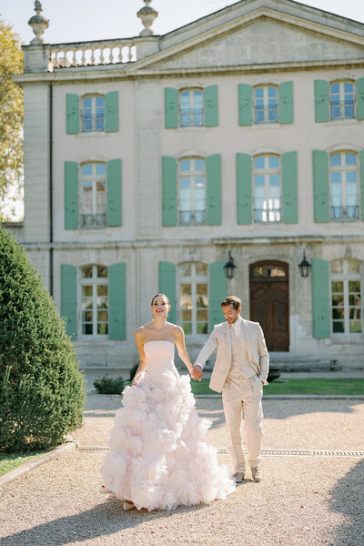 Bride and groom walking hand in hand on the grounds of Château de Tourreau during their destination wedding in France.