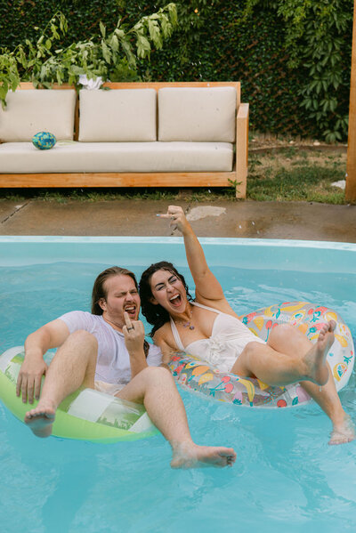 Bride and groom laying in pool floats showing off their wedding rings at their micro wedding in Boulder, Colorado