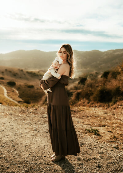Mother holding her baby in the golden so cal  sunset. 