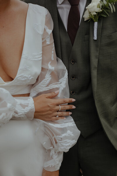 Editorial photo of bride and groom showing off textured, fashion-forward wedding attire in romantic close-up.