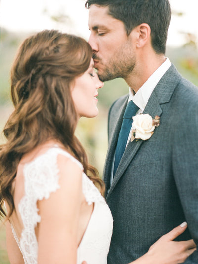 Groom kisses his bride on her forehead