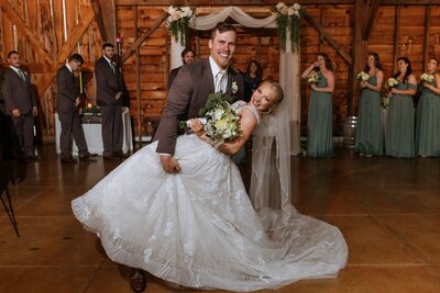 Groom dipping the bride on the dance floor, both smiling.
