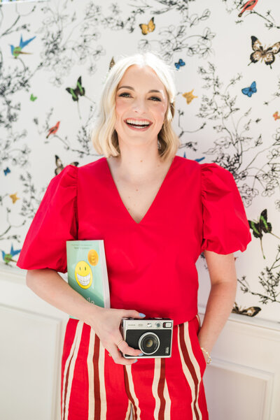 Headshot of Dr. Brooks, orthodontist in Nashville, TN, in a red outfit holding a vintage camera