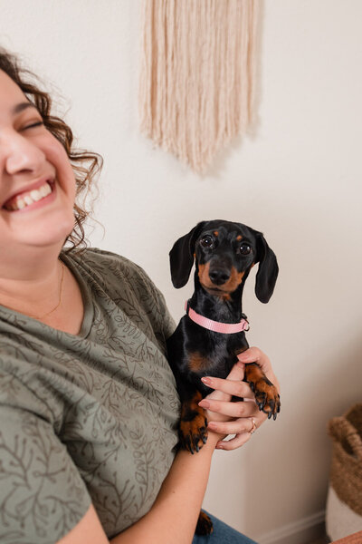 Laura holds her small pup to the camera