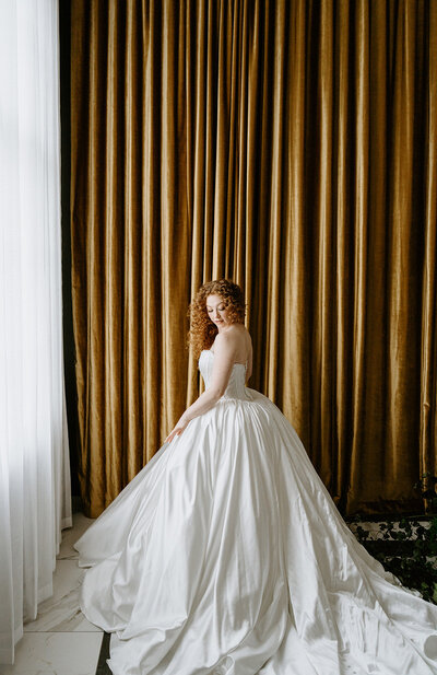 bride in strapless gown in front of gold velvet backdrop