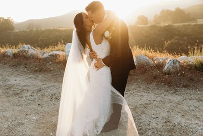 bride holding grooms face in woods