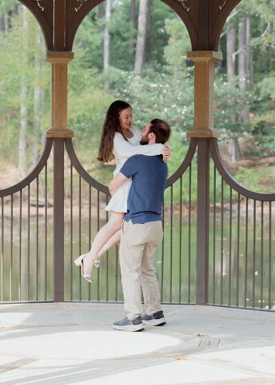 A couple spins around together under the iconic pergola at the south carolina botanical gardens at clemson university during their catholic engagement session.