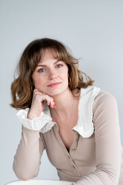 A woman, founder Hannah Van Woert, sits at a table, deep in thought and reflection.