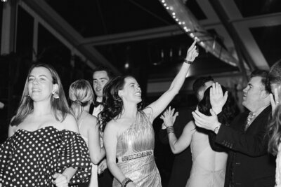 Black and white image of wedding guests dancing at a reception