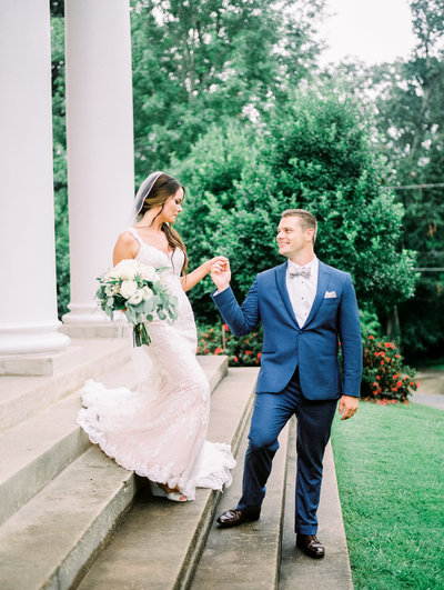 groom helping bride down the front steps at the church they got married at in columbus georgia by atlanta wedding photographer lane albers photography