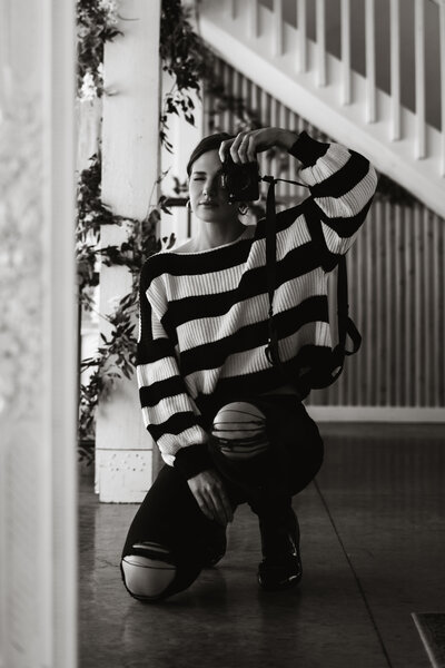 black and white photo of a woman pointing a camera back at the user