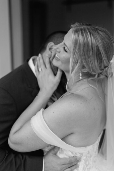 Bride and groom sharing an emotional candid moment in black and white laughing and embracing.