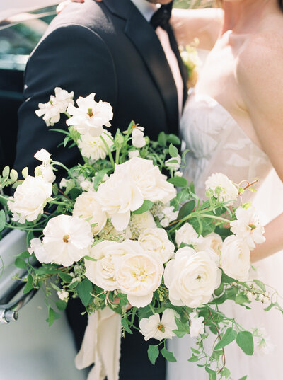Bride in Mira Zwillinger holds a white bridal bouquet
