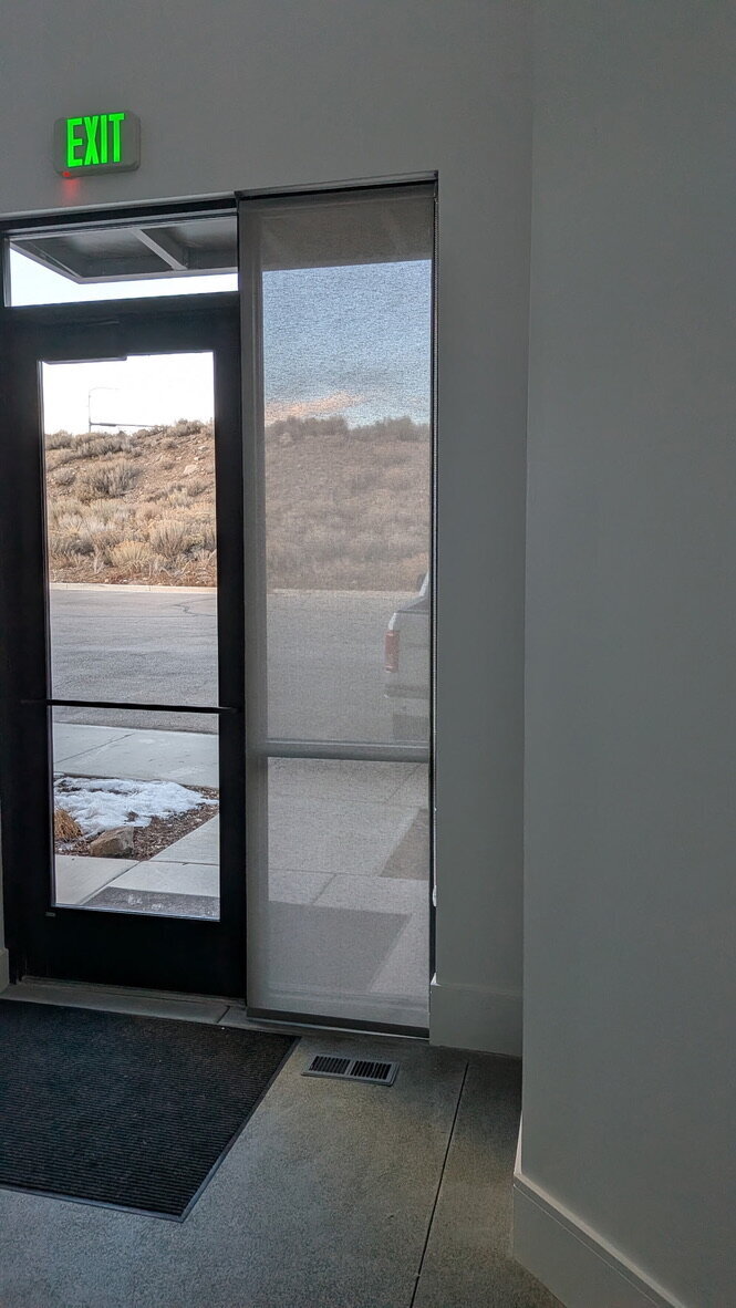 Solar shade on a lobby door sidelight below an exit sign in Park City, Utah