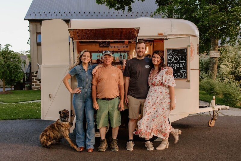 Business owners and famiy stand in front of mobile bar