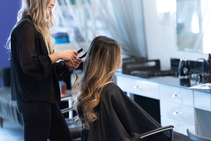 Stylist curls client's long hair