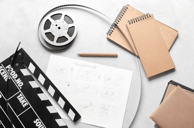 clap vidéo noir, bobine de film et une feuille avec un crayon de papier