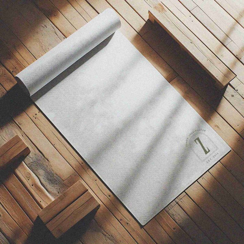 A yoga mat rests on a wooden floor beside a wooden chair in the serene Zenith Yoga and Pilates Studio