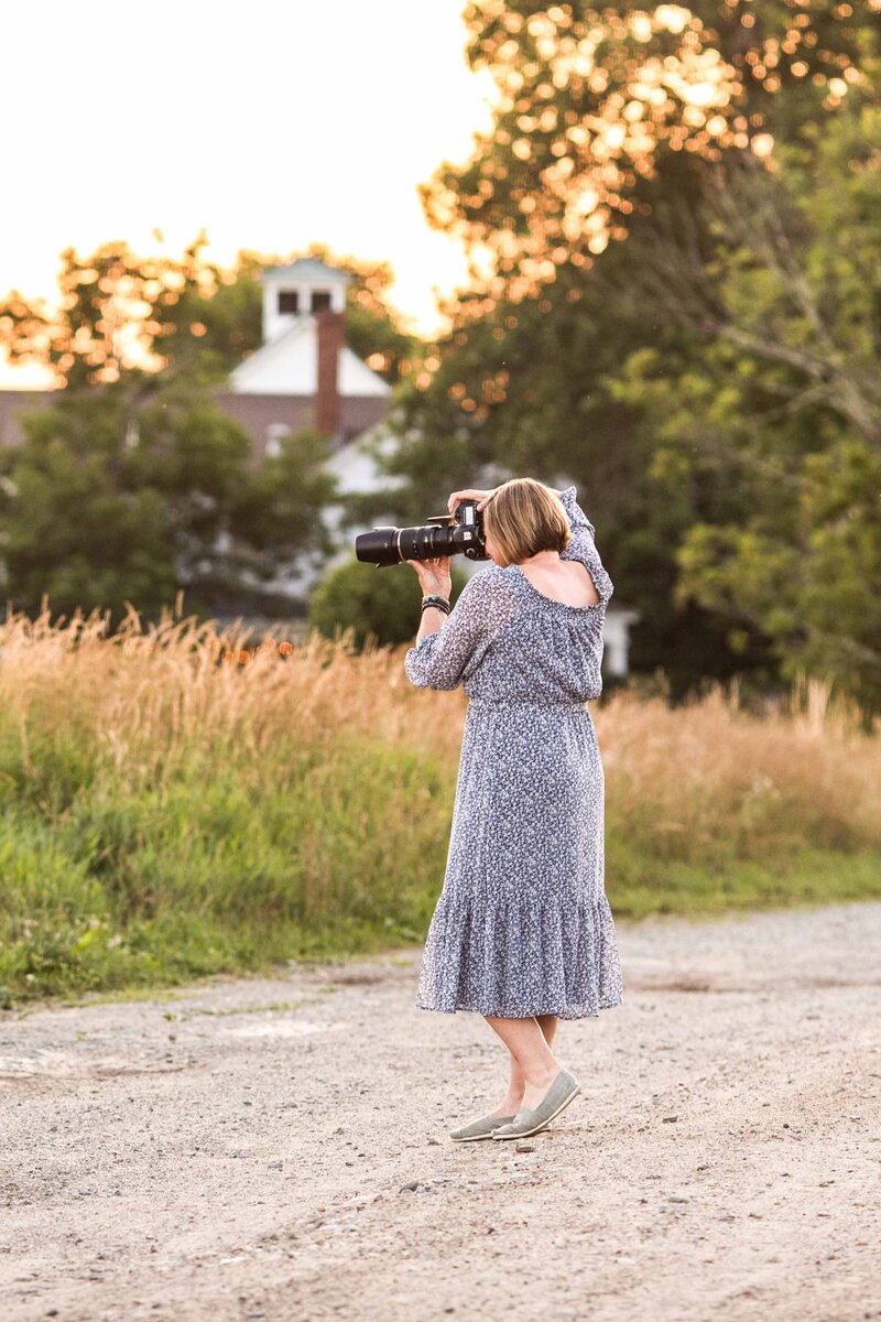 Photographer standing on a dirt road shooting into the field.