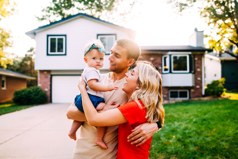 family holding baby out front of house
